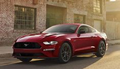 a red ford mustang parked on the side of the road in front of an old brick building