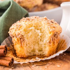 a muffin sitting on top of a white plate next to cinnamon sticks