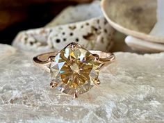 a yellow diamond ring sitting on top of a rock