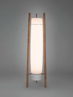 a floor lamp that is on top of a white base and wooden poles in front of it