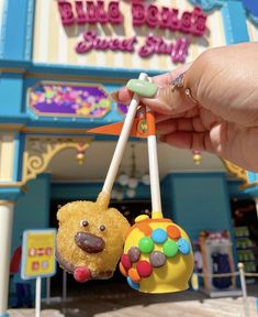 a hand holding two small toy animals in front of a building with candy on it