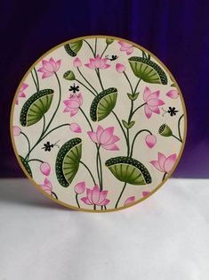 a white plate with pink flowers and green leaves on the front is sitting on a table