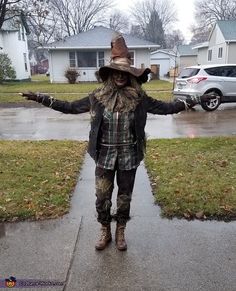 a scarecrow standing in the rain with his arms out