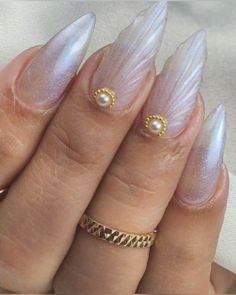 a woman's hand with some white and gold nail polishes on her nails