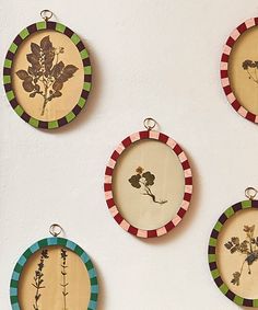 four small round wooden plaques with flowers on them hanging from the side of a wall