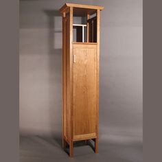 a tall wooden cabinet sitting on top of a gray floor next to a white wall