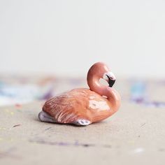 a pink toy flamingo sitting on top of a floor next to a white wall