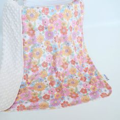 a white and pink flowered blanket hanging from a hook