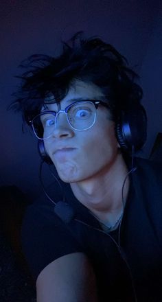 a man wearing headphones and glasses in the dark