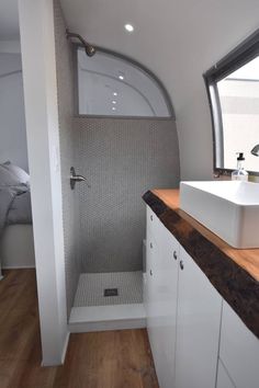 a white sink sitting under a bathroom window next to a wooden counter top in front of a mirror