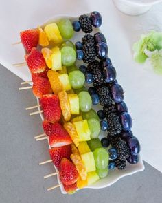 fruit skewers are arranged on a white plate