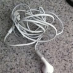 there is a white headphone on the floor with wires attached to it and an earbud plugged in