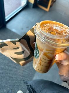 someone holding up a starbucks cup with caramel and orange syrup in it's wrapper