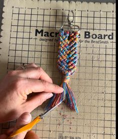 a person is holding scissors and stringing the beads on a piece of paper that has been made into a keychain