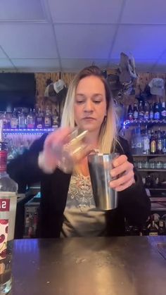 a woman holding a cup in front of a bar