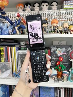 a person holding up a cell phone in front of a shelf with figurines