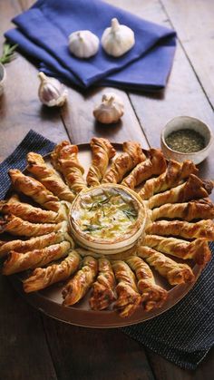 an assortment of breads on a plate with dip in the middle and garlic sprouts next to it