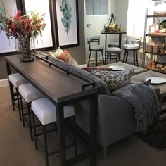 a living room filled with lots of furniture next to a dining table and bar stools