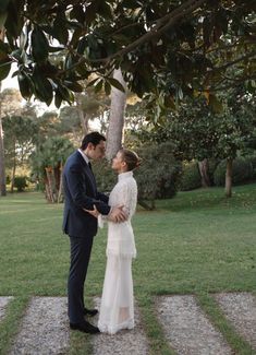 a man and woman standing next to each other in front of a lush green field