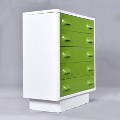 a green and white cabinet with drawers on it's sides, against a gray background