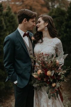 a bride and groom standing together in the woods