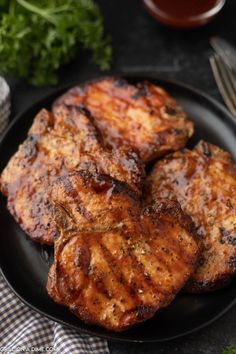 grilled pork chops on a black plate with garnish