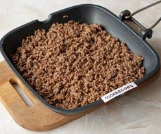 a pan filled with food sitting on top of a wooden cutting board next to a spatula