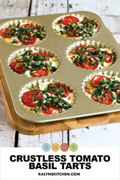 a muffin tin filled with mini pizzas topped with tomatoes and spinach leaves