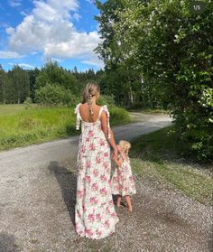 a mother and daughter walking down a dirt road