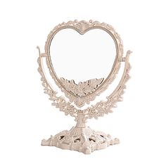 a white heart shaped mirror sitting on top of a metal stand with an ornate design