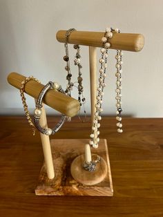 a wooden stand with several necklaces and rings hanging from it's sides on top of a wood table