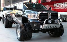 a black dodge ram truck parked in front of a red and white bus on the street