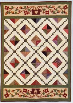 a quilted wall hanging on the side of a white wall with red and green accents