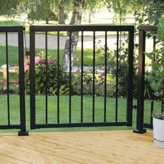 a wooden deck with black railing and potted plants