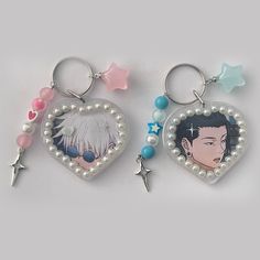 two heart shaped key chains with charms attached to them, one has an anime character on it