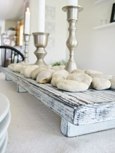 a table topped with lots of donuts on top of a wooden tray next to two candles