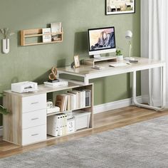 a desk with a computer on top of it in front of a green wall and wooden floors