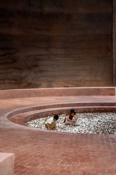 two people are sitting in the middle of a circular area with rocks and gravel around them