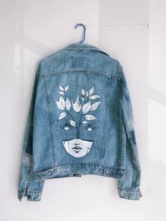 a denim jacket with an image of a woman's face painted on the back