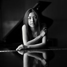 black and white photo of a woman sitting in front of a piano with her arms crossed