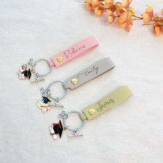 three personalized keychains sitting next to each other on a white tablecloth