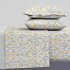 three pillows stacked on top of each other with yellow and white designs in them,