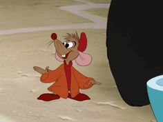 a cartoon mouse standing in the sand next to a trash can