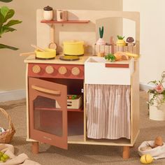 a wooden toy kitchen with an oven, sink and stove top on carpeted floor