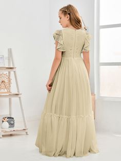 a woman in a long dress is looking down at the wall and she has her back to the camera