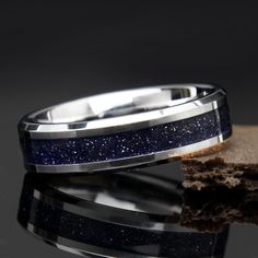 a wedding band with blue glitter inlays on top of a piece of wood