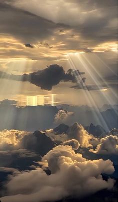 the sun shining through clouds over mountains