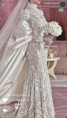 a woman in a wedding dress holding a bouquet and looking at the back of her gown