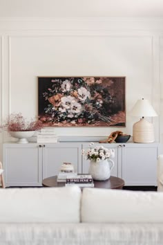 a living room filled with furniture and a painting on the wall above it's coffee table