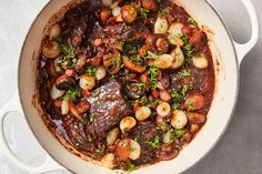 a pot filled with stew and vegetables on top of a table next to a spoon